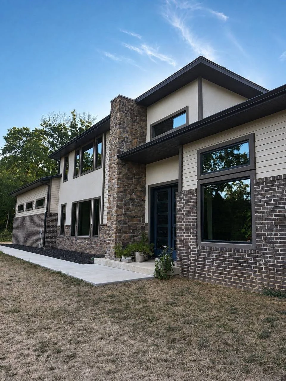 Contemporary house with stone and brick exterior, large windows, covered entry, and landscaping